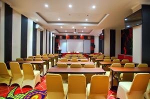 une salle de conférence avec des tables, des chaises et un écran dans l'établissement Swiss-Belcourt Makassar, à Makassar