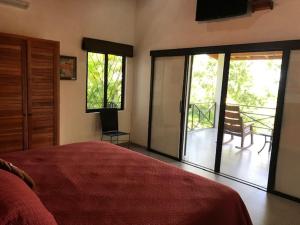 a bedroom with a bed and sliding glass doors with a balcony at Villas Lambeau Ocean View 1 in Uvita