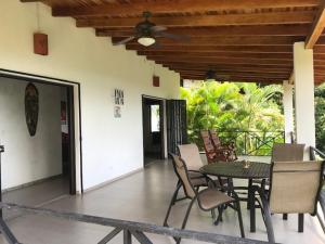 a patio with a table and chairs on a porch at Villas Lambeau Ocean View 1 in Uvita