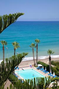 a swimming pool with palm trees and the beach at Hotel Za Maria in Santo Stefano di Camastra