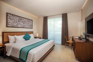 a bedroom with a bed and a desk and a television at Anja Jimbaran in Jimbaran