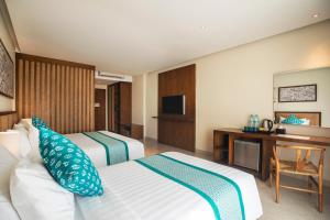 a hotel room with two beds and a television at Anja Jimbaran in Jimbaran