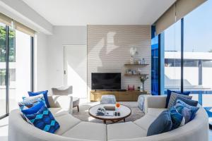 Mövenpick Luxury Villa2FL-Private Pool-SHA CERTIFIED في نا جومتين: غرفة معيشة مع أريكة بيضاء ووسائد زرقاء