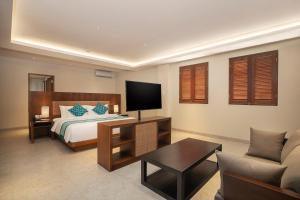 a bedroom with a bed and a tv and a couch at Anja Jimbaran in Jimbaran