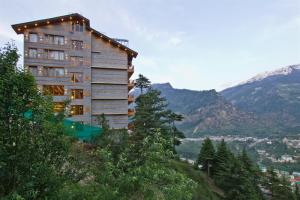 wysoki budynek na wzgórzu z górami w tle w obiekcie The Holiday Villa Resorts & Spa w mieście Manāli