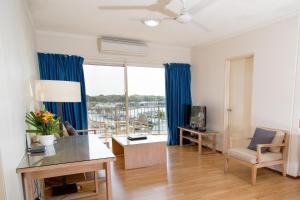 ein Wohnzimmer mit blauen Vorhängen und einem großen Fenster in der Unterkunft Cullen Bay Resorts in Darwin