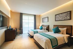 a hotel room with two beds and a flat screen tv at Anja Jimbaran in Jimbaran