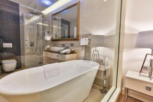 a white bathroom with a tub and a sink at Hotel Rivijera in Petrovac na Moru