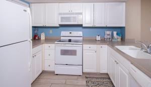 a kitchen with white cabinets and a white stove top oven at Sunswept 203 Condo in Orange Beach