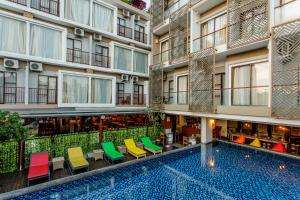 an apartment building with a swimming pool and colorful chairs at Metland Seva Seminyak - Formerly Horison Ultima Seminyak in Seminyak