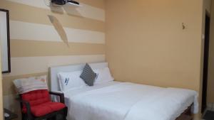 a bedroom with a white bed and a red chair at PGR Thirunallar in Karaikal
