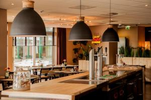 a restaurant with tables and chairs and pendant lights at Hotel Dekkers in Ossendrecht