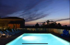 ein Schwimmbad in der Nacht mit Stühlen und einem Zaun in der Unterkunft Agriturismo Mascudiera in Fiorenzuola dʼArda