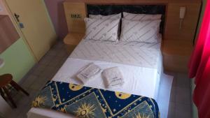 uma cama com lençóis brancos e almofadas num quarto em Hotel Lado Leste em São Paulo