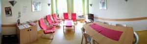 a waiting room with red chairs and a table at Jugendherberge Friedrichstadt in Friedrichstadt