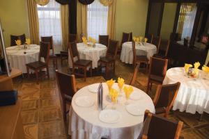 a dining room with white tables and chairs at Pensiunea Medina in Cheia