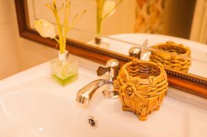 a bathroom sink with a faucet in front of a mirror at Tum Baan Suan ตุ่มบ้านสวน in Chanthaburi