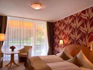 a hotel room with a bed and a table and a window at Hotel Burgblick in Badenweiler