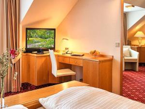 a bedroom with a desk with a television and a bed at Hotel Burgblick in Badenweiler