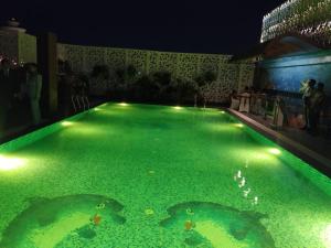 a swimming pool with green water at night at Hotel Millenia Regency Lucknow in Lucknow