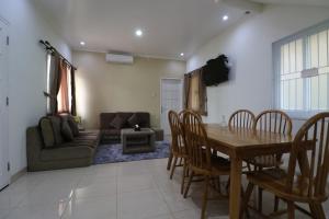 ein Wohnzimmer mit einem Tisch, Stühlen und einem Sofa in der Unterkunft Diyar Villas Puncak H8/7 in Puncak