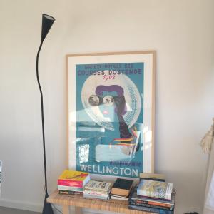 a framed poster of a woman on a table with books at sea and city view with double terrace Flat C Oostende in Ostend