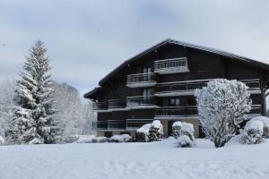 a building covered in snow with trees in the foreground at Chalet des pistes in Megève