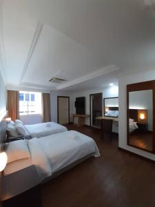 a large bedroom with two beds and a mirror at Sara Hotel in Labuan
