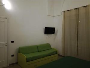 a living room with a green couch and a television at La casa di Mela in Leverano