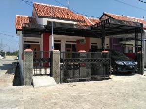 ein Haus mit einem Tor und einem Auto, das darunter geparkt ist in der Unterkunft WIEN HOMESTAY CIREBON - B7 Family Homestay in Cirebon