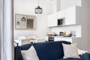 ein Wohnzimmer mit einem blauen Sofa und einer Küche in der Unterkunft JOIVY Luxurious 2BR Apt with street view, 2mins to Santa Justa Lift in Lissabon