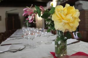 un tavolo con un vaso con fiori gialli di Biobagnolese Agriturismo a Orte Altre 37 foto