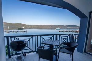 een balkon met stoelen en een grill en uitzicht op een meer bij Laguna Grove Holiday Rentals in Knysna
