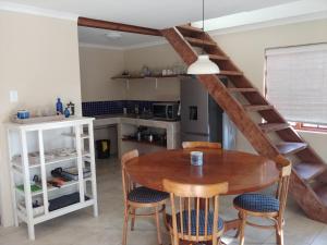 una cocina con mesa de madera y sillas y una escalera en Wild Hare Cottages en Lions River