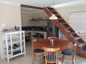 a kitchen with a wooden table and chairs and a staircase at Wild Hare Cottages in Lions River
