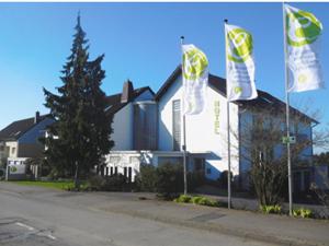 un bâtiment avec deux drapeaux devant lui dans l'établissement Hotel Eikamper Höhe, à Odenthal