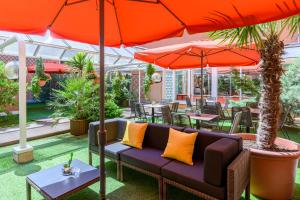 a patio with a couch and tables and umbrellas at Citadines Wilson Toulouse in Toulouse