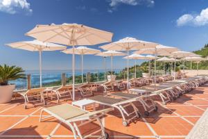 une rangée de tables et de chaises avec parasols dans l'établissement Madrigale Panoramic Lifestyle & Soulful Hotel, à Costermano