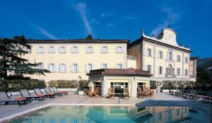 a large building with a pool in front of it at Il Balconcino sulle Terme in San Giuliano Terme