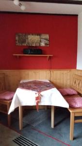 a room with a bed and two benches against a red wall at Ferienwohnung Tihsies in Seddin