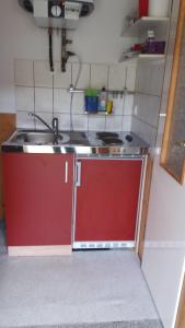 eine Küche mit einem Waschbecken und einem roten Schrank in der Unterkunft Ferienwohnung Tihsies in Seddin
