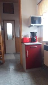 eine Küche mit einem roten Schrank und einer Mikrowelle in der Unterkunft Ferienwohnung Tihsies in Seddin