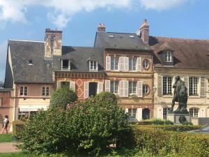 une grande maison avec une statue en face de celle-ci dans l'établissement Maison de charme Beaumont, proche Deauville, à Beaumont-en-Auge