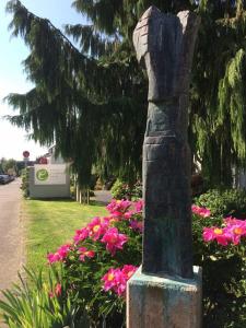 une statue dans un jardin avec des fleurs roses dans l'établissement Hotel Eikamper Höhe, à Odenthal