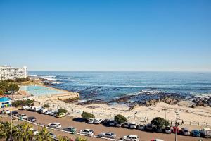 Blick auf den Strand mit geparkten Autos und das Meer in der Unterkunft First Group Riviera Suites in Kapstadt
