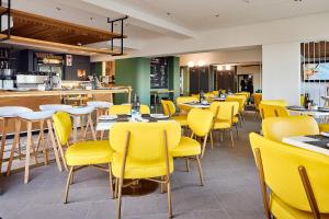 a dining room with yellow chairs and tables at First Group Riviera Suites in Cape Town