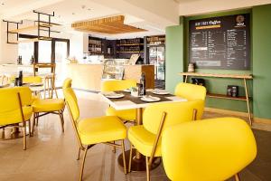 un restaurant avec des chaises jaunes, une table et un tableau noir dans l'établissement First Group Riviera Suites, au Cap 127 autres photos