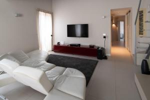 ein Wohnzimmer mit einem weißen Sofa und einem Flachbild-TV in der Unterkunft La Boheme di Ortigia Luxury - Ortigia Holidays in Syrakus