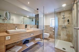 a bathroom with two sinks and a glass shower at Landhotel Moorhof in Neuschönau