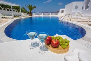 a tray of fruit and wine glasses next to a swimming pool at Santorini View in Akrotiri +37 photos